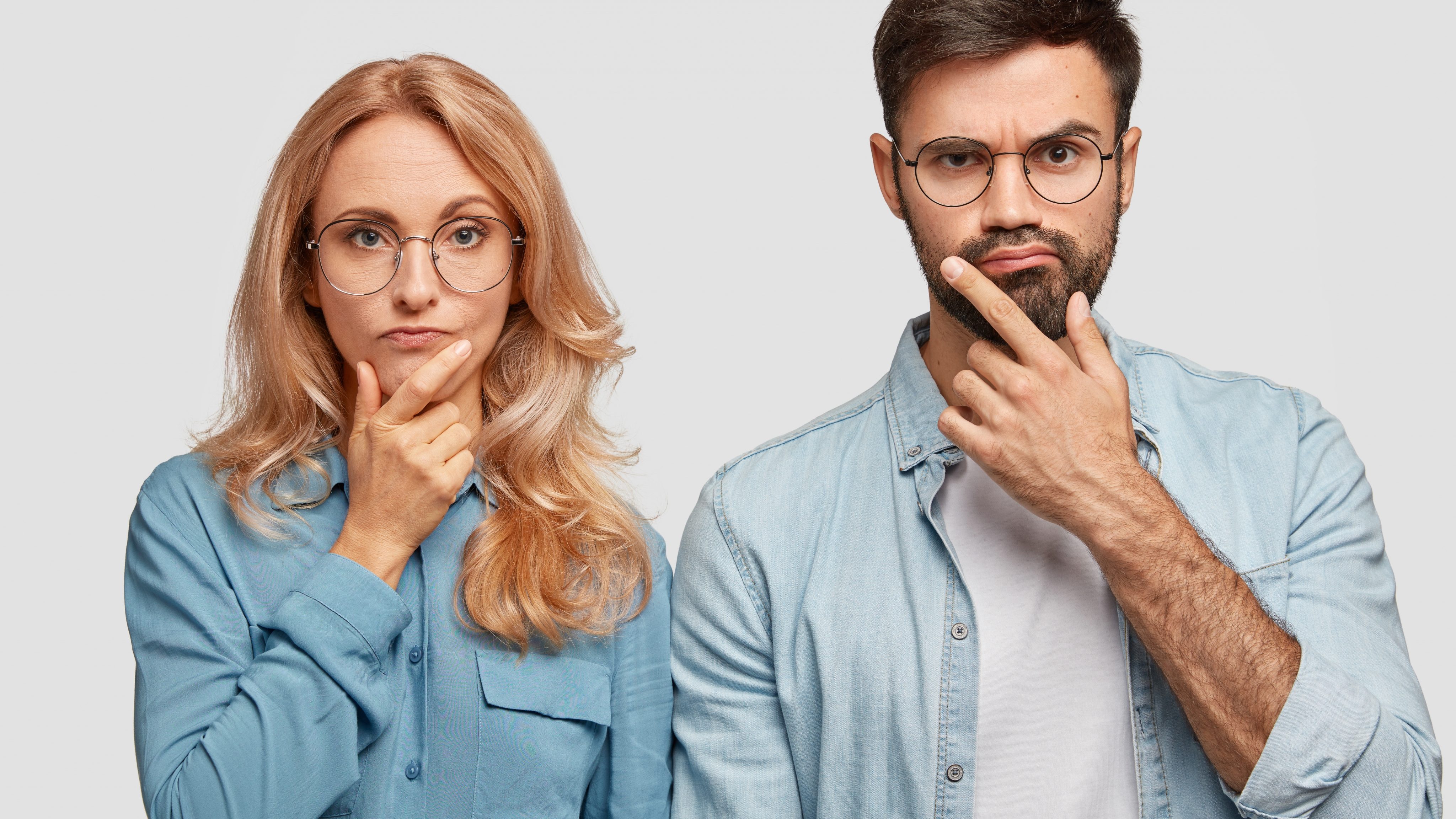 Thoughtful man and woman colleagues hold chins and being concentrated on solving problem look directly