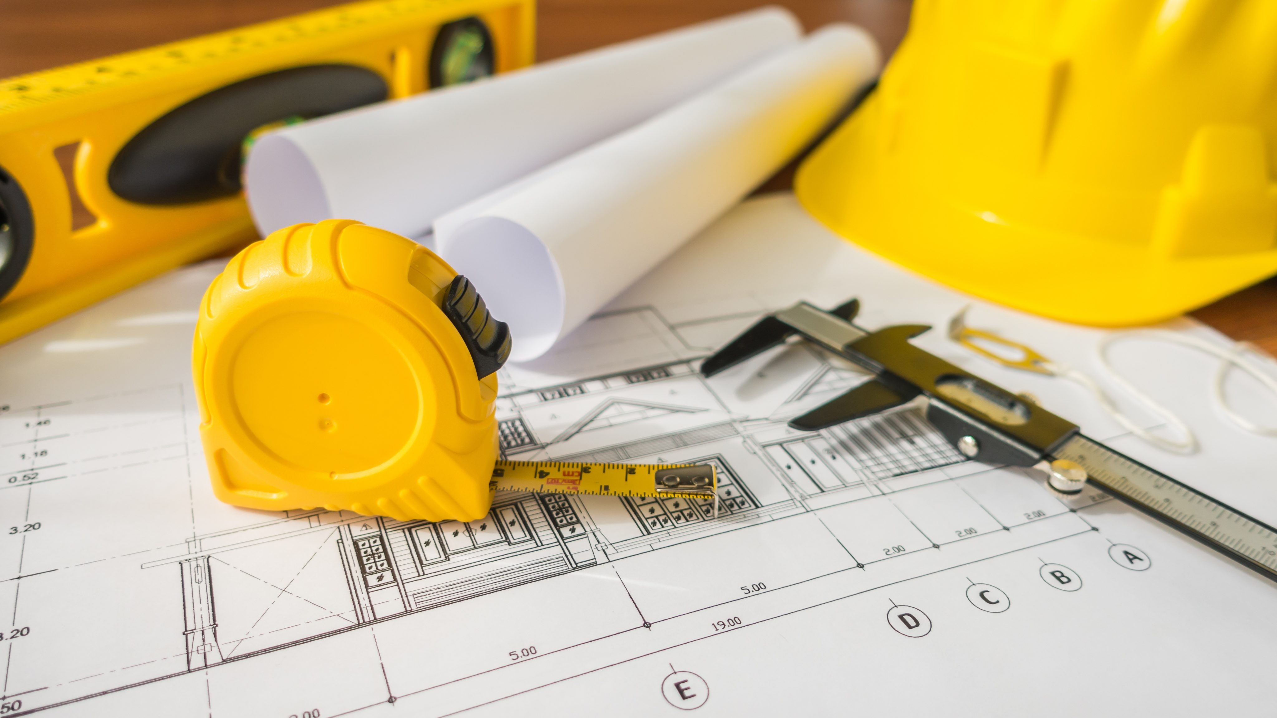 Construction plans with yellow helmet drawing tools bluep