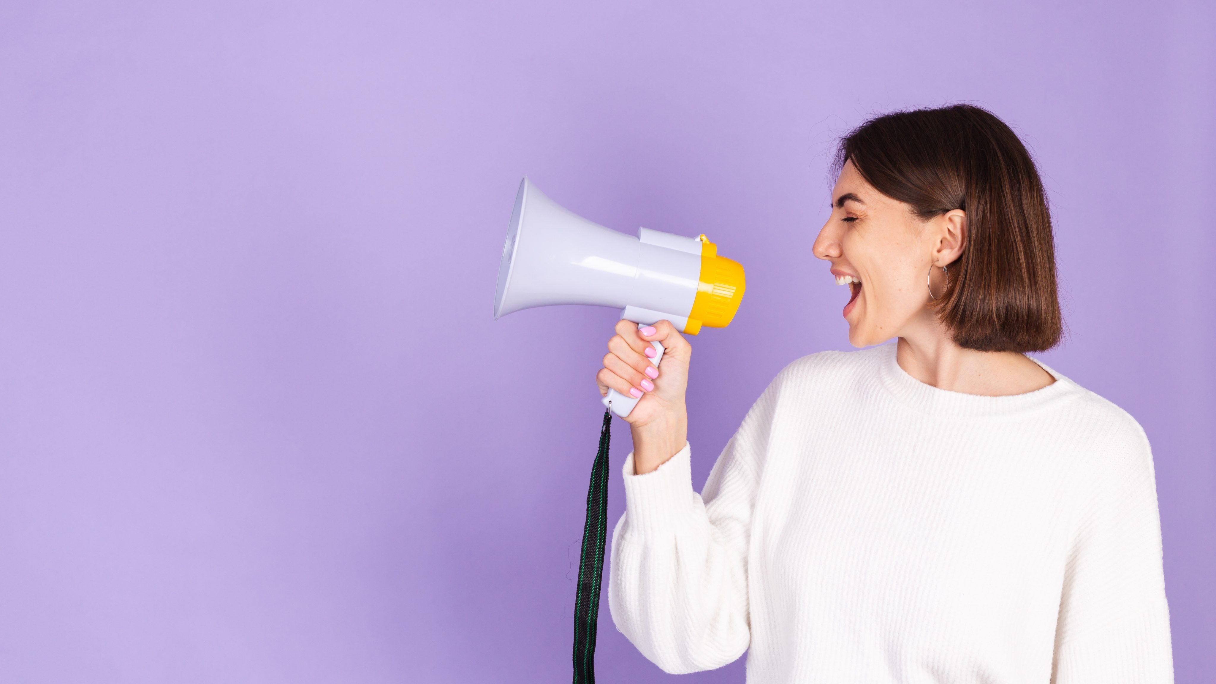Young brunette white casual sweater isolated purple wall