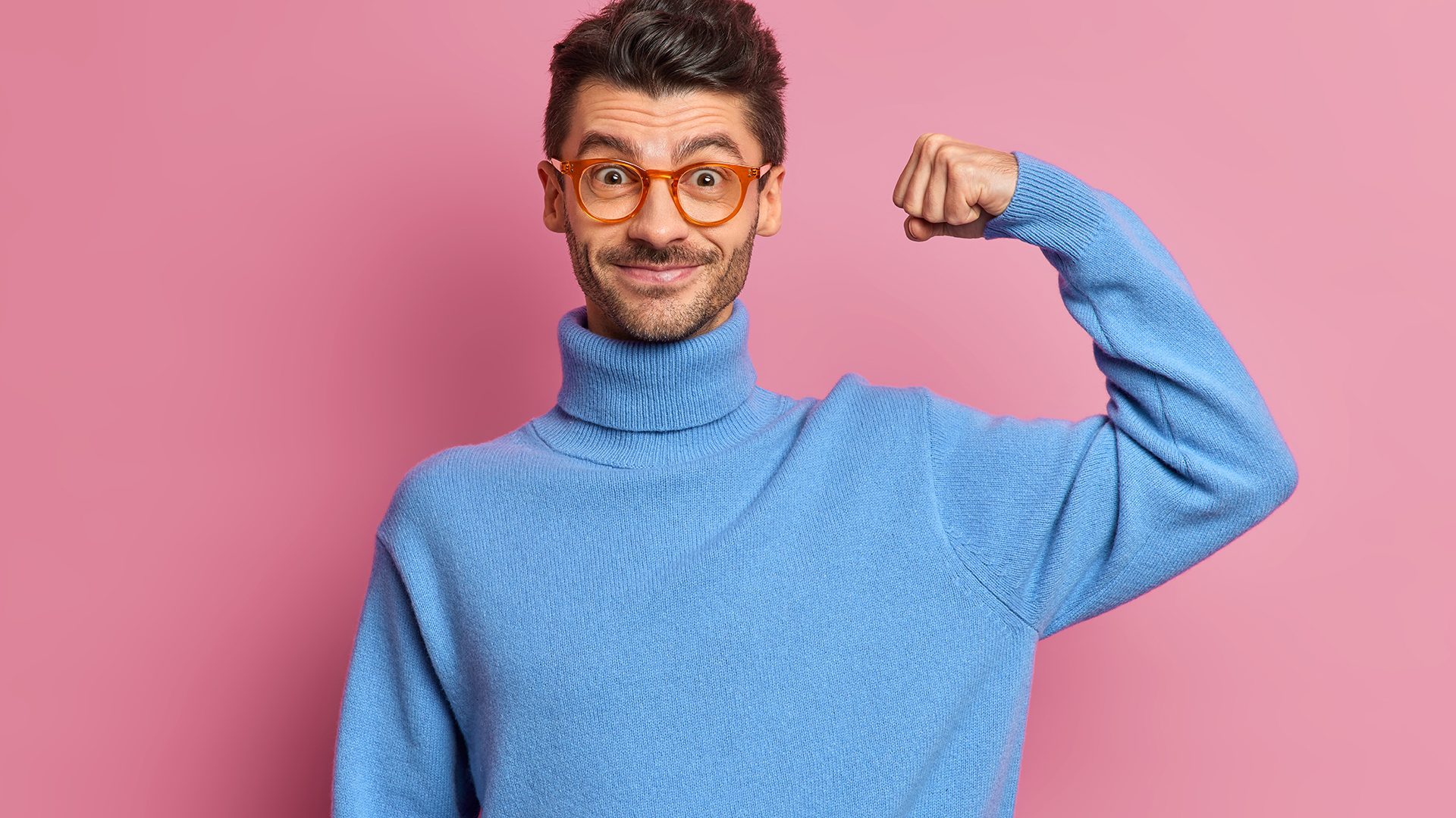 Self confident cheerful unshaven man raises arm shows muscles feels power