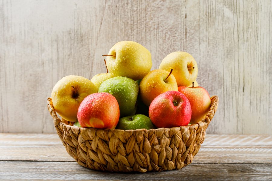 Apples with drops wicker basket light wooden grunge