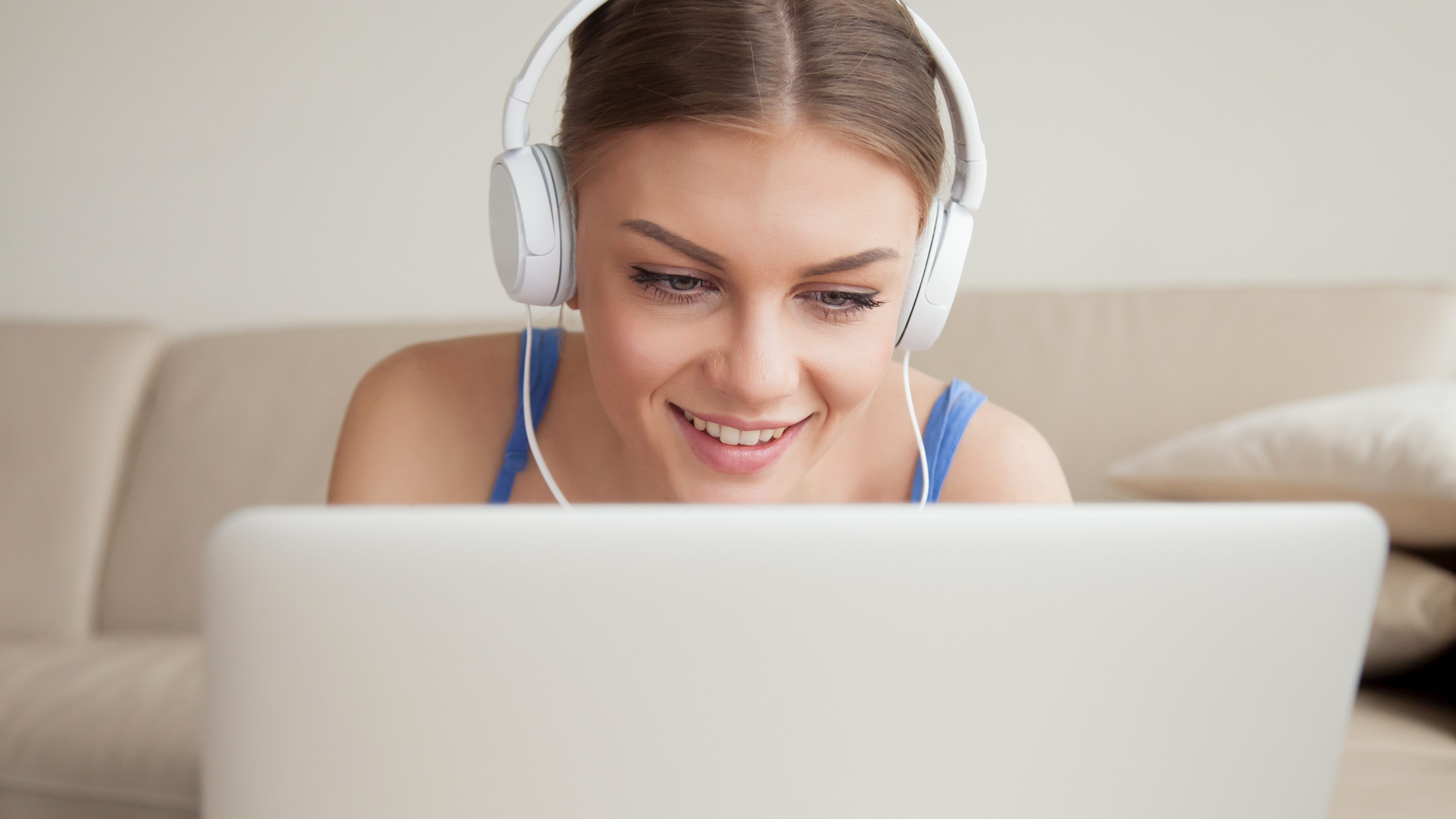 Smiling young woman wearing headphones using laptop headshot