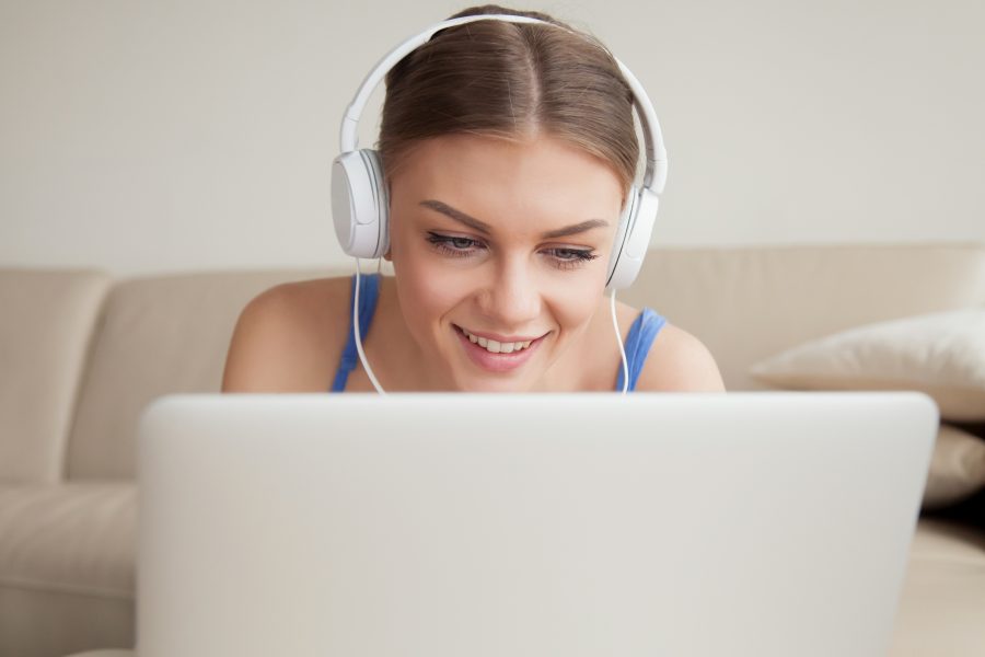 Smiling young woman wearing headphones using laptop headshot